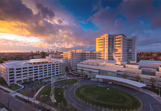 Aerial view of UC Davis Medical Center with sun setting in the distance shining a golden glow on the hospital. 
